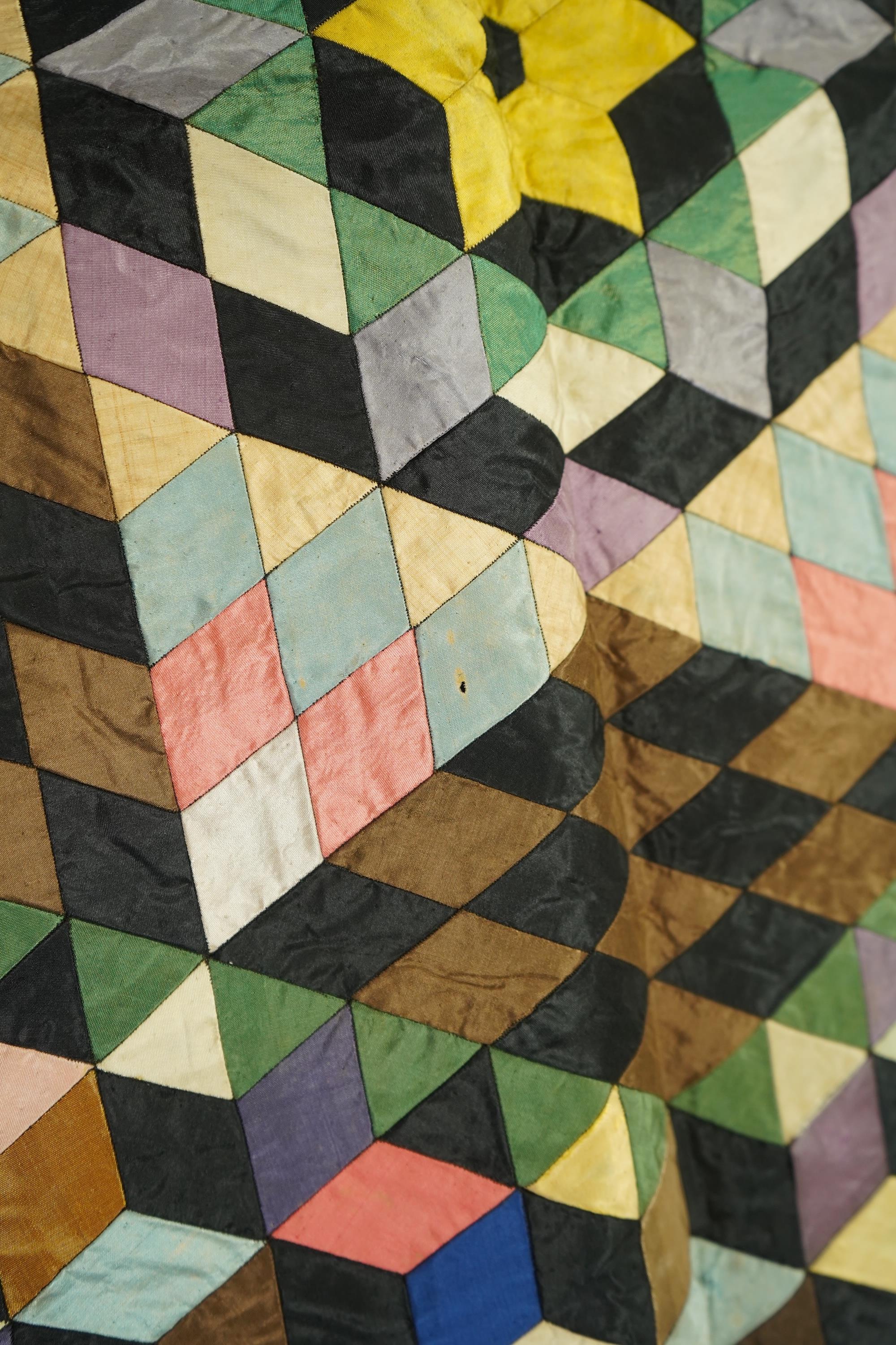 An English 19th century silk ‘Tumbling Blocks’, hand sewn, patchwork quilt, with central star motif and wide velvet border. Worked with multi coloured silks backed with black and blue silk., 170cm x 152cm. Condition - th